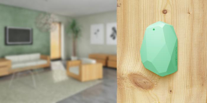 A green ultra-wideband (UWB) Estimote beacon deployed on a wall.