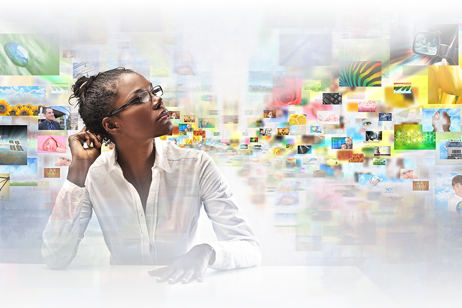 A businesswoman sits thinking in front of photo collage background.