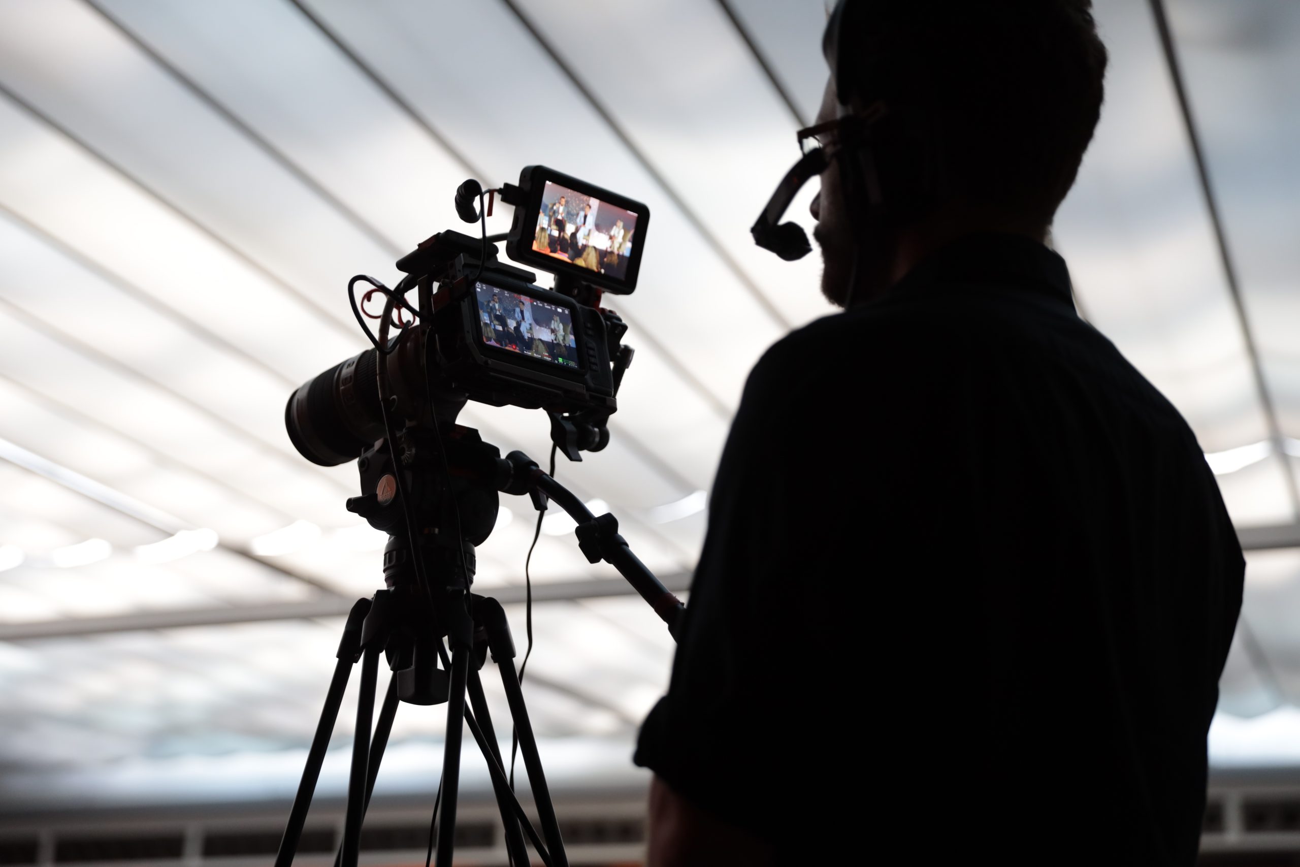 Shadowed view of a Brella event management agency videographer recording a live, corporae event presentation.