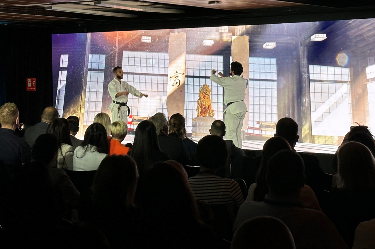 Brella event management agency-design, corporate meeting opening featuring a martial arts demonstration in front of a video backdrop of a dojo.