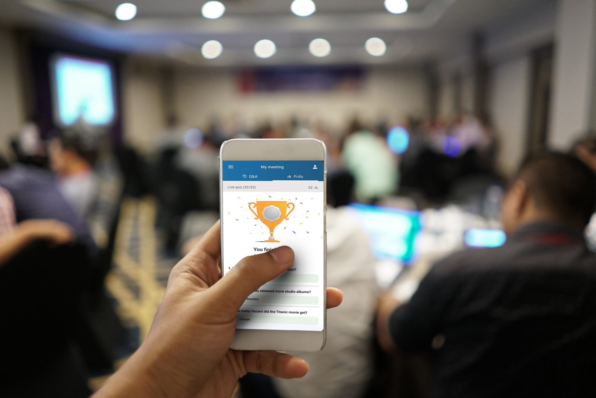 Closeup of a hand using a smartphone event app during a live conference.