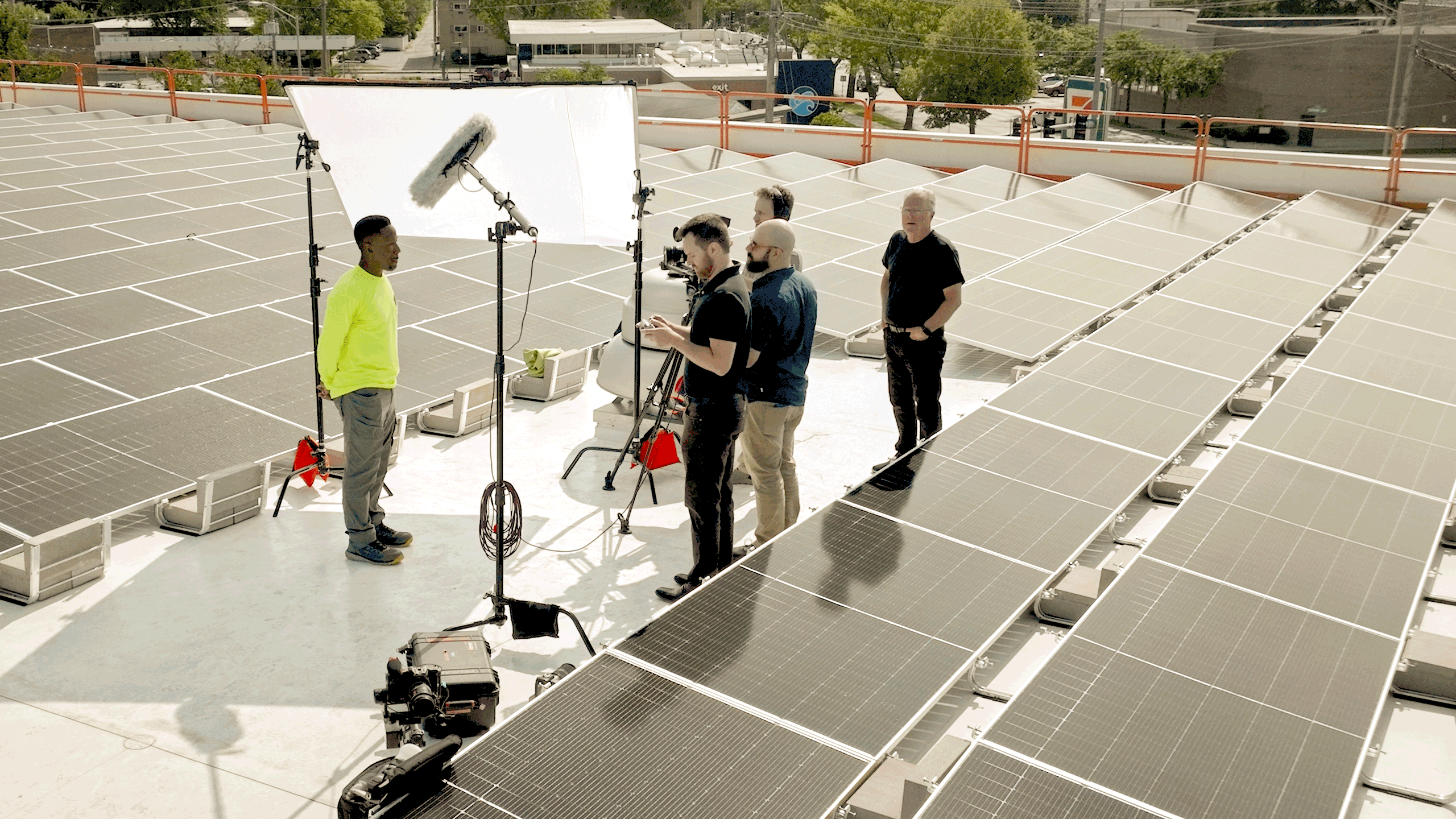 Brella Productions' video production team films a rooftop interview during a solar panel installation.