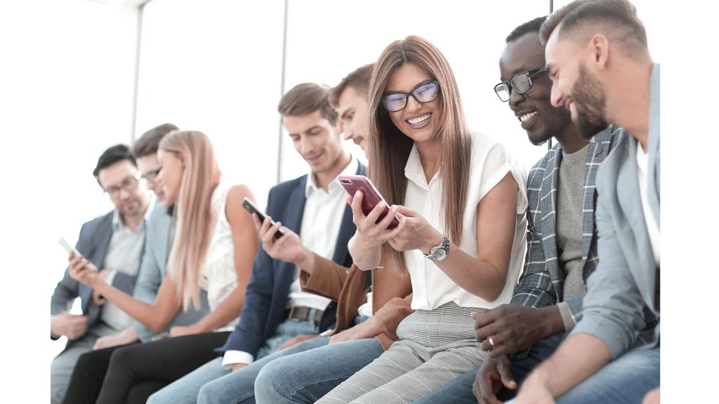 Small groups of multicultural colleagues looking at shared phone screens.